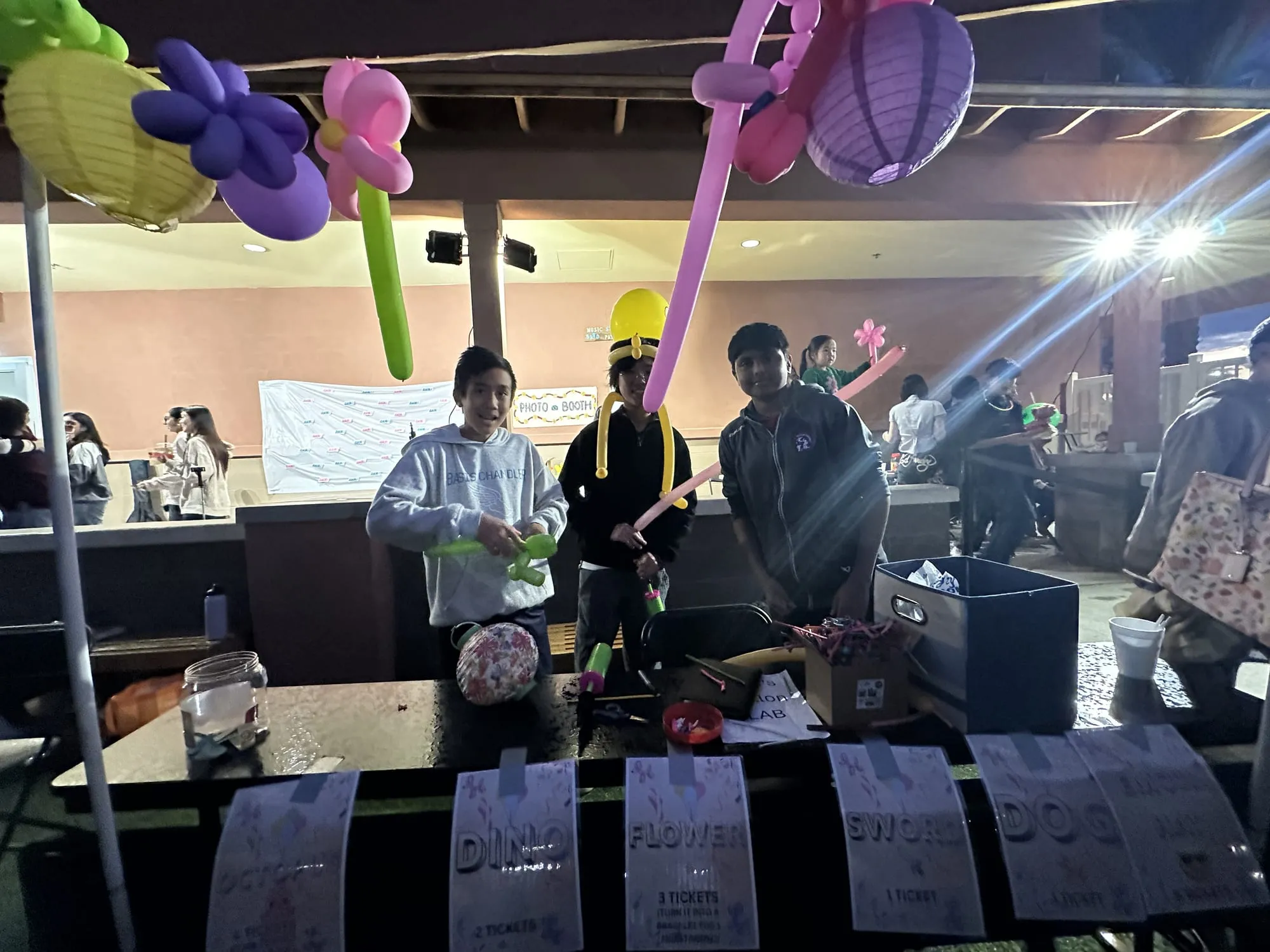Students holding balloon animals at a game booth at night