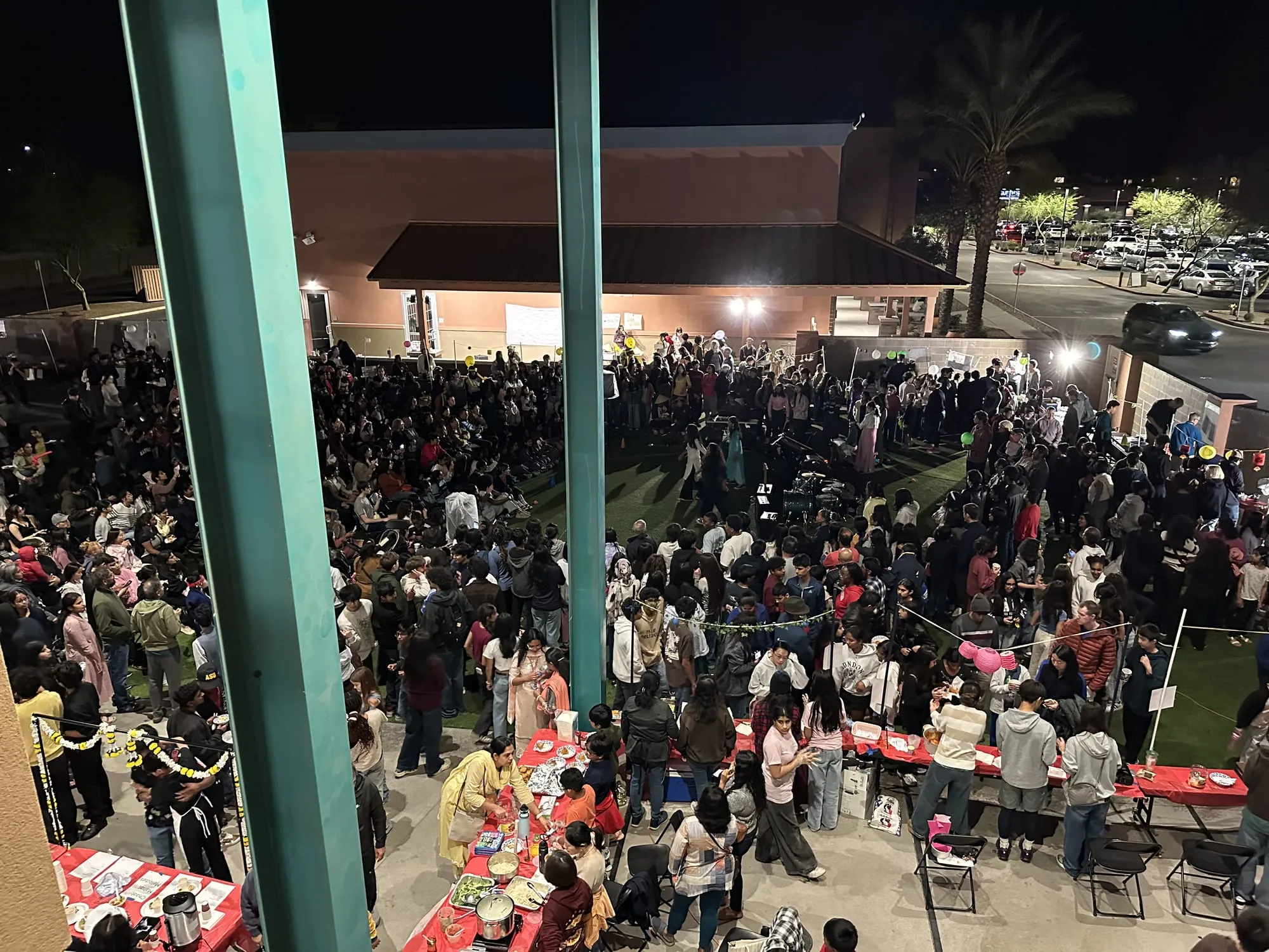 A packed crowd fills the courtyard at night, seen from above