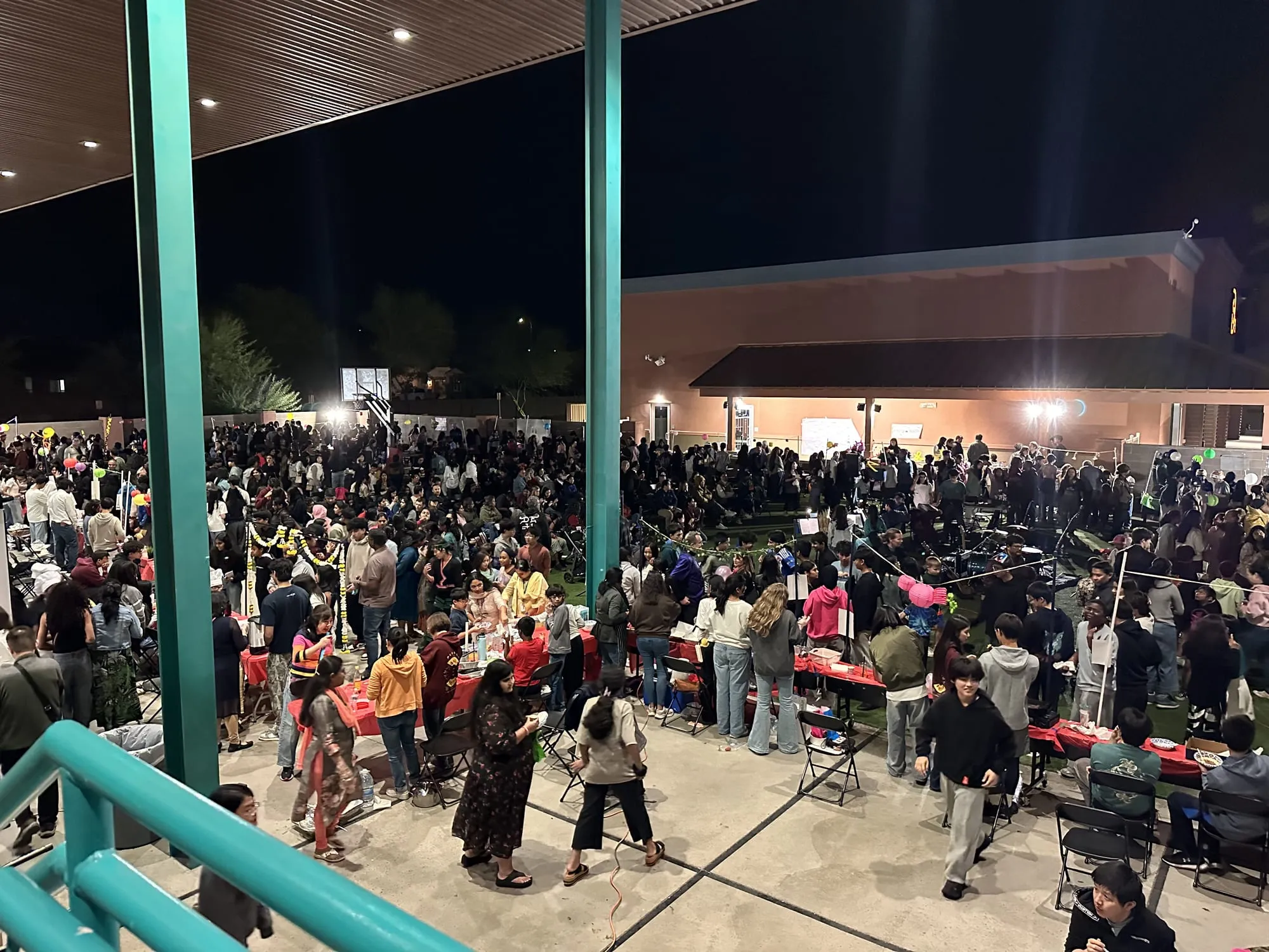 People dance and mingle in the crowded courtyard at night