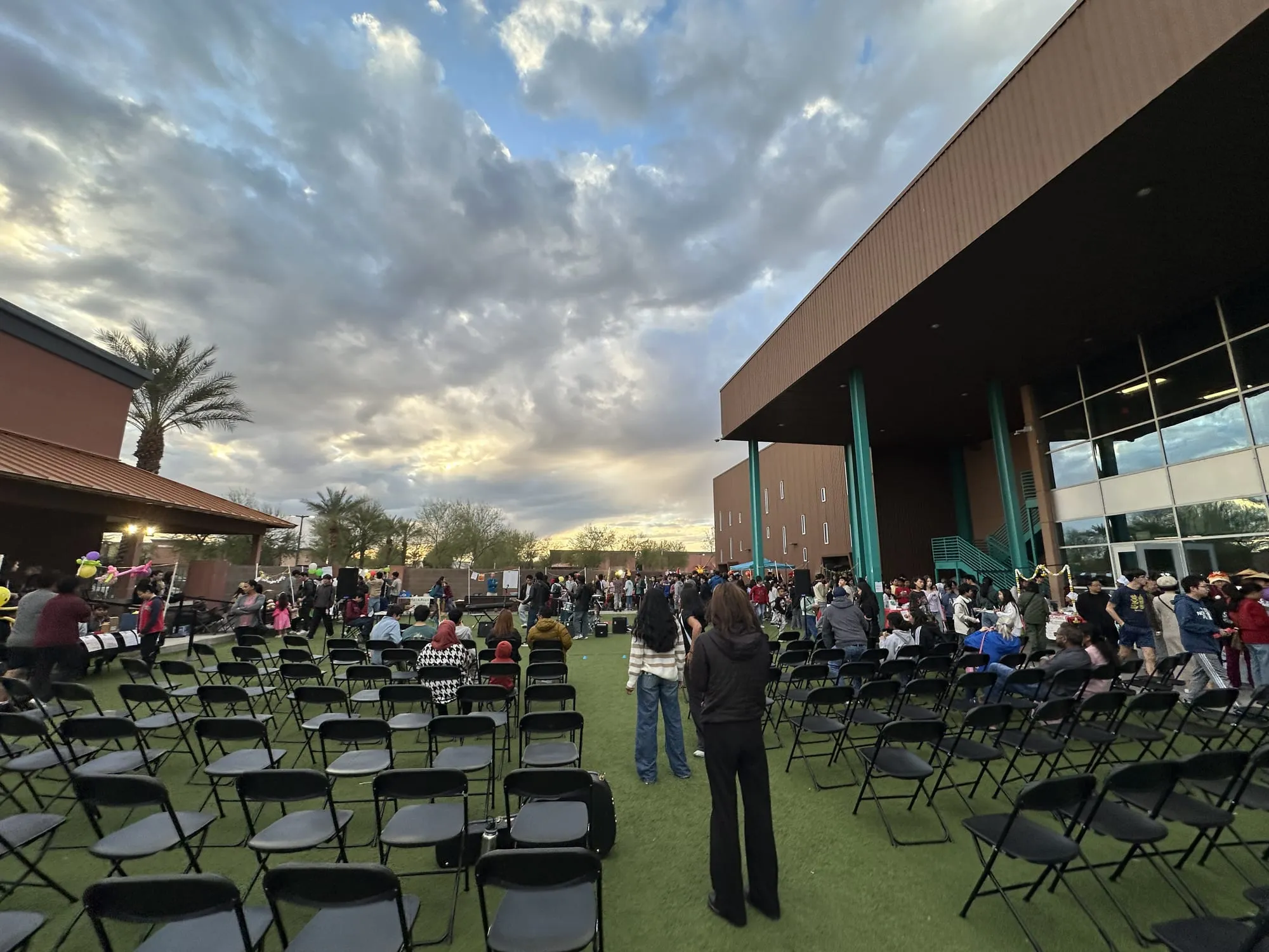 Crowds arrive on the lawn as the sky turns orange at dusk