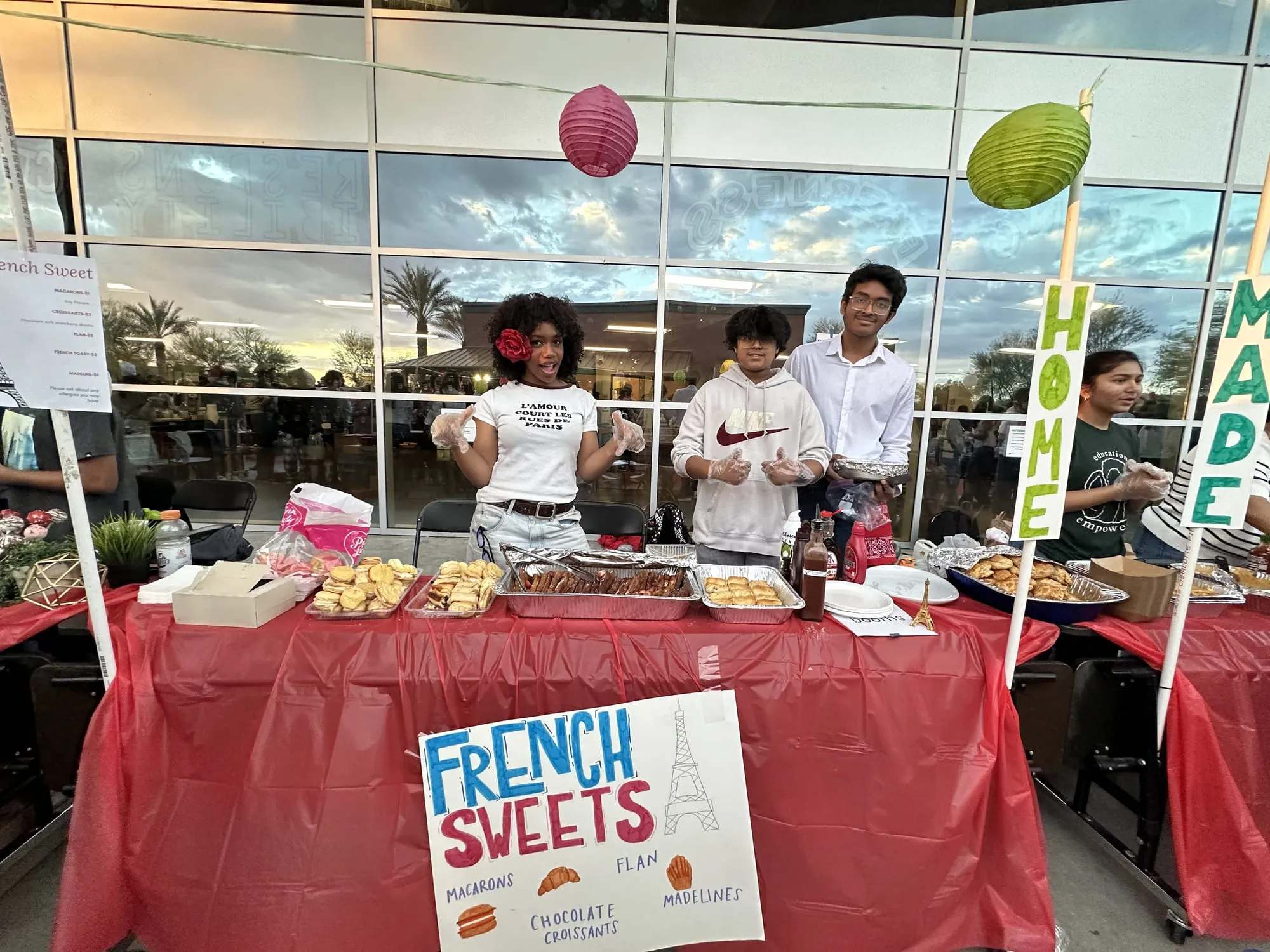 Students behind a long table of pastries with a French Sweets sign